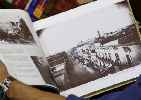 Imagen secundaria 1 - Arriba, detalle de la biblioteca del escritor y académico. Sobre estas líneas, Pérez-Reverte ojea uno de sus volúmenes. A la derecha, detalles del escritorio y sus inmediaciones