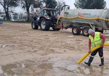 Un operario extrae agua de un charco en una de las calles de la aldea con un camión autobomba